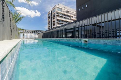 una gran piscina junto a un edificio en House of Charlie Pinheiros, en São Paulo