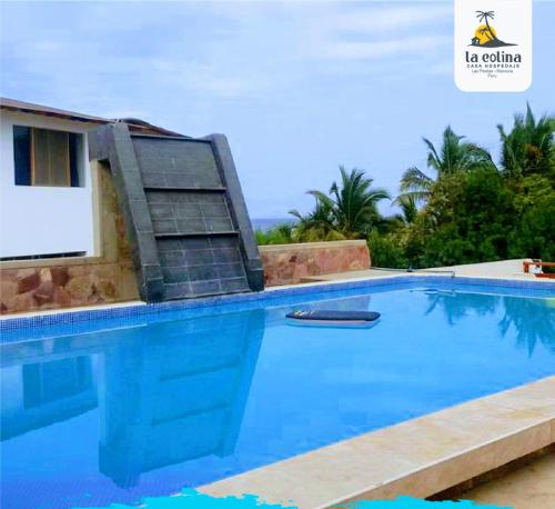 a large blue swimming pool with a chair next to it at LA COLINA Casa-Hospedaje in Máncora