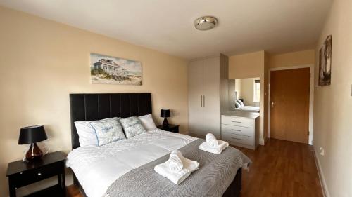 a bedroom with a large bed with two towels on it at Stylish 2 Bedroom Flat near Warner Studios in Watford