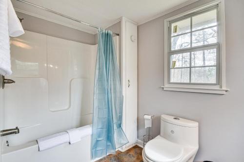 La salle de bains blanche est pourvue de toilettes et d'une fenêtre. dans l'établissement Peaceful Tallassee Cottage on 2 Acres!, à Tallassee