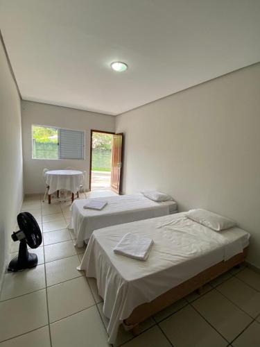 two beds in a room with a table and a window at Villa do Lago in Poços de Caldas