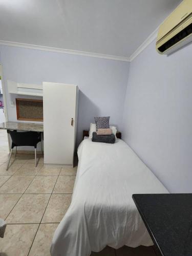 Dieses weiße Zimmer verfügt über ein Bett und einen Schreibtisch. in der Unterkunft Elina Self catering in Ongwediva