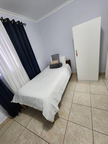 a small bedroom with a bed with a blue curtain at Elina Self catering in Ongwediva