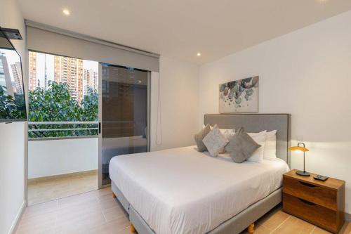 een slaapkamer met een wit bed en een groot raam bij Spacious 2 bedroom apartment in the heart of Provenza in Medellín