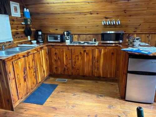 a kitchen with wooden cabinets and a stove top oven at A-Frame Cabin #5 with Hot Tub on Patoka Lake in Southern Indiana in Paoli
