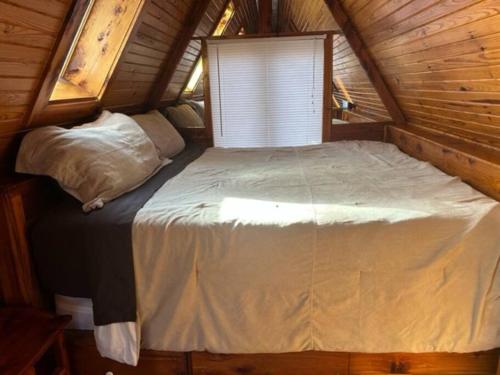 a large bed in a wooden cabin with a window at A-Frame Cabin #6 with Hot Tub on Patoka Lake in Southern Indiana in Seymour