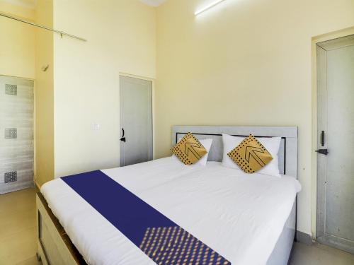 a bedroom with a white bed with yellow and blue pillows at OYO Hotel Mount View in Haldwāni
