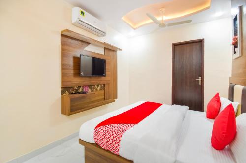 a bedroom with a bed with red pillows and a tv at OYO Flagship Hotel Classico Inn in Jaipur