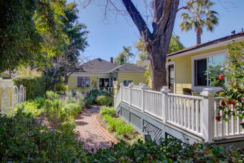 a white fence in front of a yellow house at Secret Garden Inn & Cottages in Santa Barbara