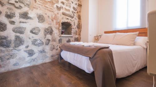 Un dormitorio con una pared de piedra y una cama en Apartamentos Zocosol by Toledo AP en Toledo