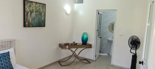 Cette chambre blanche dispose d'une table avec un vase bleu. dans l'établissement Zeyden Place Apt, à Praia