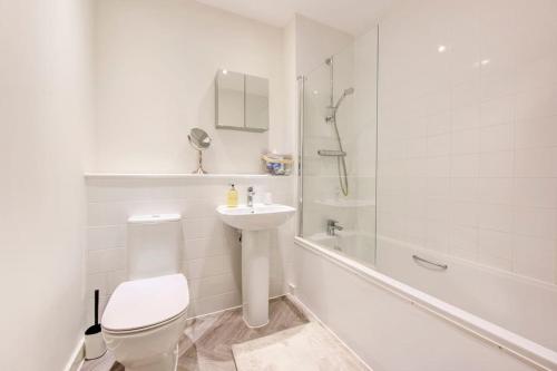 a white bathroom with a toilet and a sink at Beautifully furnished 3-bed apartment near Wembley Stadium in Wealdstone