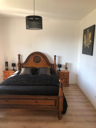 una camera con letto in legno e 2 comodini di Gîte "Le Millésime 61" a Flavigny