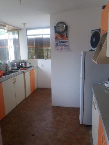 a kitchen with a refrigerator and a clock on the wall at LA COLINA Casa-Hospedaje in Máncora