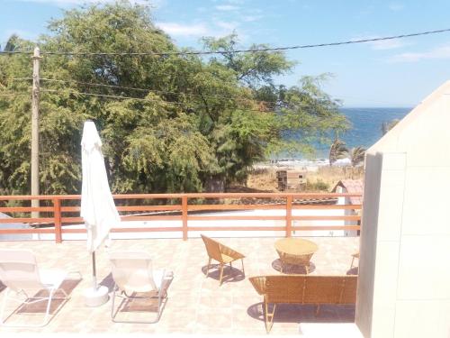a patio with chairs and a white umbrella at LA COLINA Casa-Hospedaje in Máncora