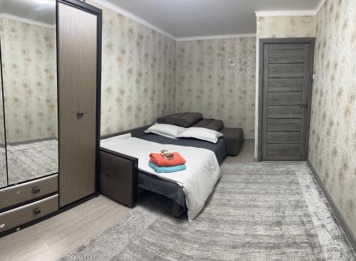 a bedroom with a bed and a dresser and a mirror at Апартаменты 2-х и 1 комнатные in Taraz