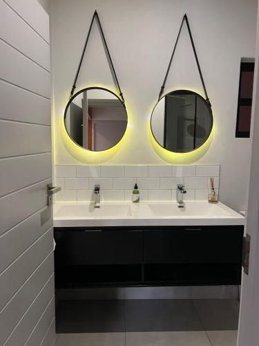 a bathroom with two sinks and two mirrors at The Fitz Apartment in Johannesburg