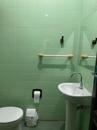 a green bathroom with a toilet and a sink at Hotel Ceres - suíte Artista Helo - 25 in Cuiabá