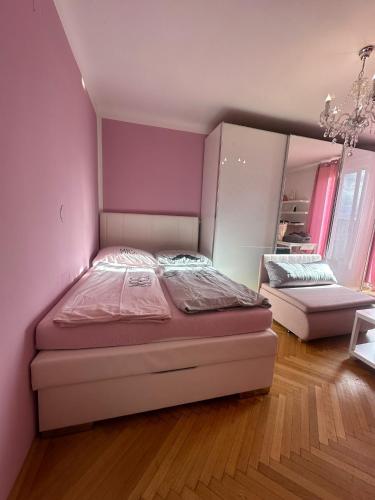 ein Schlafzimmer mit einem Bett und einer rosa Wand in der Unterkunft 1Bedroom Apartment in Wien