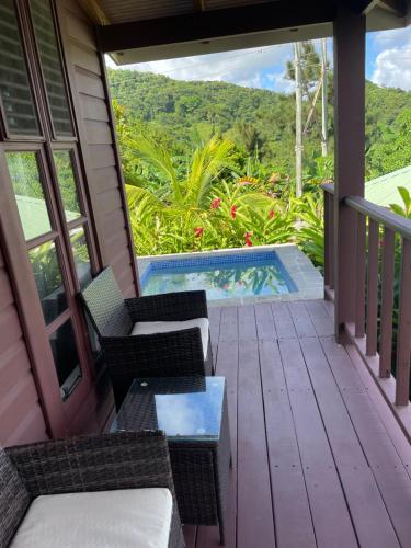 a porch with chairs and a table and a swimming pool at Montete Cottages in Choiseul