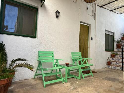 two green chairs and a table next to a building at Apartamento con terraza Delta Slow in Deltebre