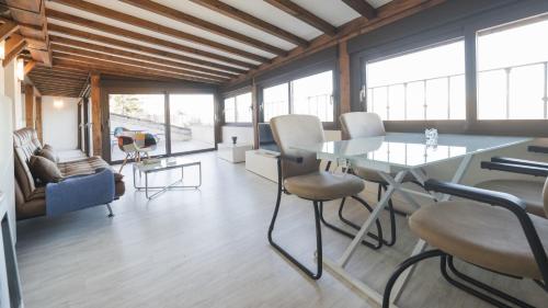 Cette chambre comprend une table, des chaises et des fenêtres. dans l'établissement Apartamentos Zocosol by Toledo AP, à Tolède
