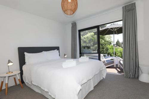 a bedroom with a white bed and a large window at Rad Little Pad in Rotorua