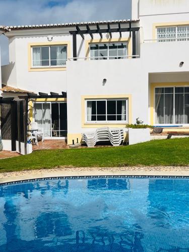 a house with a swimming pool in front of a house at Casa Da Praia in Luz