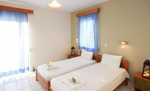 a hotel room with two beds and windows at Studios Afrodite in Chrysi Ammoudia