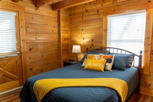 a bedroom with a bed with wooden walls and windows at Heavenly Peace in Pigeon Forge