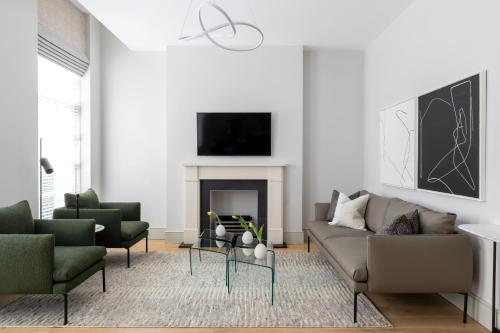 a living room with a couch and two chairs and a fireplace at AKA Marylebone in London