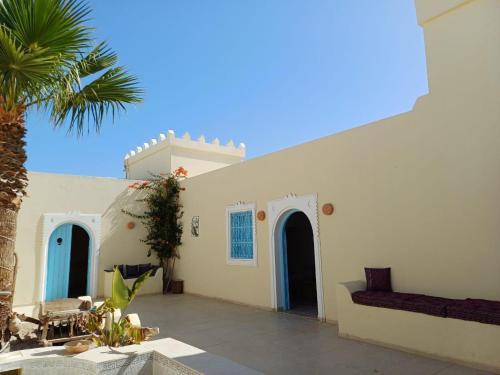 biały budynek z niebieskimi drzwiami i palmą w obiekcie DAR EL JERBIA w mieście Midun