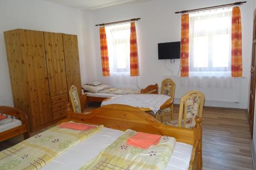 a room with three beds and a tv and windows at Borostyán Vendégház in Alsóregmec