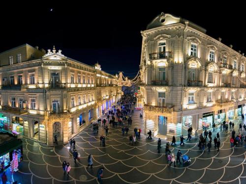 a group of people walking around a street at night at KING Hostel in Center in Baku