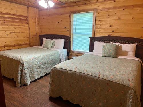 a bedroom with two beds in a log cabin at Solarium Deluxe Cabin #19 on Patoka Lake in Southern Indiana in Seymour