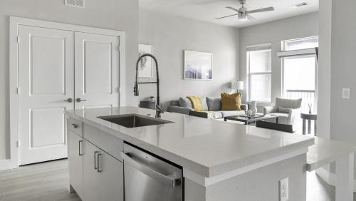 een witte keuken met een wastafel en een woonkamer bij Landing Modern Apartment with Amazing Amenities (ID1802X53) in Austin