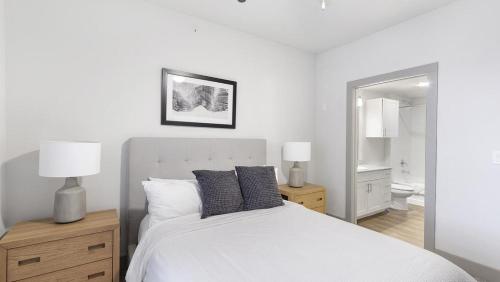 1 dormitorio con 1 cama blanca con 2 lámparas y espejo en Landing Modern Apartment with Amazing Amenities (ID1802X99), en Haltom City