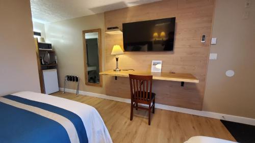 a bedroom with a bed and a desk with a television at Harbour Light Motel in Nanaimo