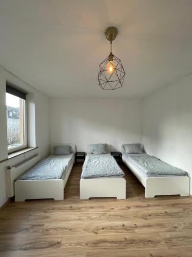 Cette chambre comprend deux lits et un lustre. dans l'établissement Wohnung in Stadtnähe Düren, à Düren
