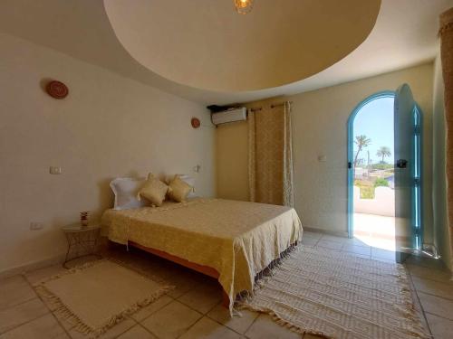 a bedroom with a bed and a large window at Dar El Jerbiya in Midoun