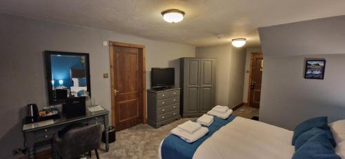 a bedroom with a bed and a desk and a television at Station Inn B&B in Kendal