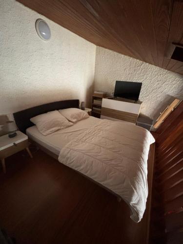 a bedroom with a bed and a desk with a laptop at Duplex rénové dans résidence privé proche de toutes commodités place de parking inclu in La Bourboule