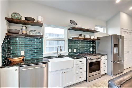 a kitchen with white cabinets and green tile on the walls at La Puerta Rosada - Gorgeous home w Private Pool in Port Aransas