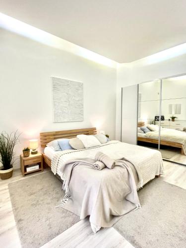 a white bedroom with a large bed and a mirror at JAMES BOND Apartment TOP Location Air Conditioned in Bratislava