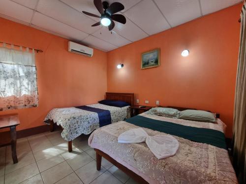 2 camas en una habitación con paredes de color naranja en Ometepe House en Moyogalpa