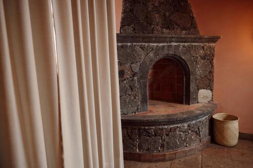 a stone fireplace in a room next to a curtain at Maison Mexique Hotel Boutique San Miguel de Allende in San Miguel de Allende