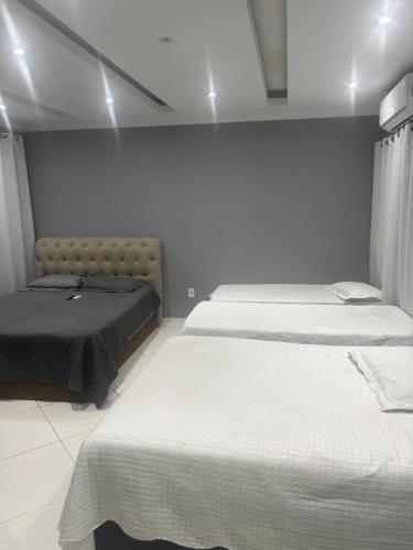 2 Betten in einem Zimmer mit weißen Wänden in der Unterkunft Casa traineras in Arraial do Cabo
