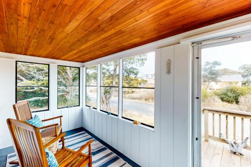 a porch with two chairs and a wooden ceiling at Vitamin Beach 12 in Avon