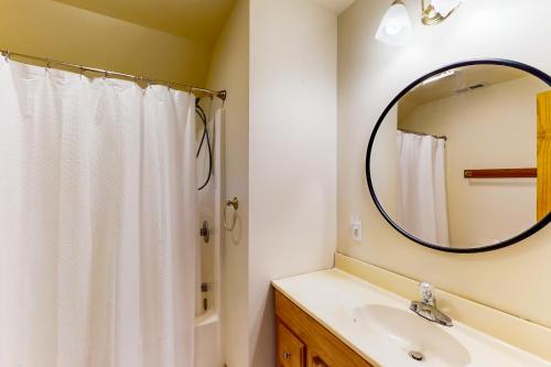 a bathroom with a white shower curtain and a mirror at Vitamin Beach 12 in Avon
