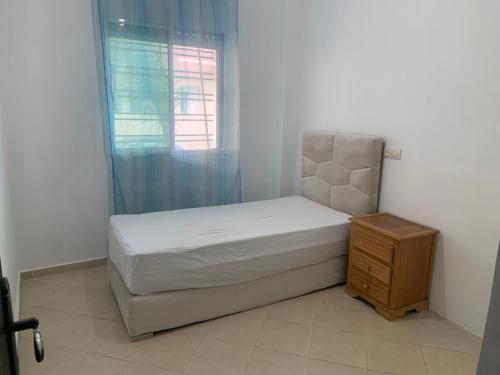 um pequeno quarto com uma cama e uma janela em Bel appartement au calme, proche du centre ville em Kenitra